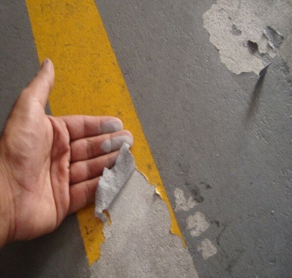Piso industrial de concreto com epóxi descascado, trincas e desgaste